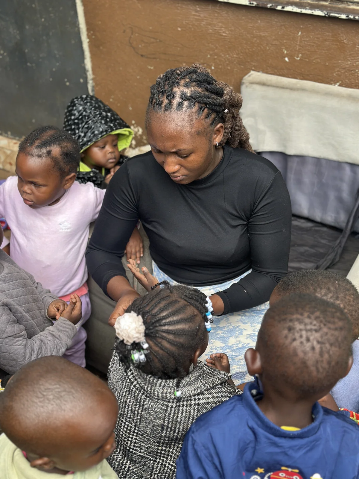 A caregiver sitting closely with children during the day