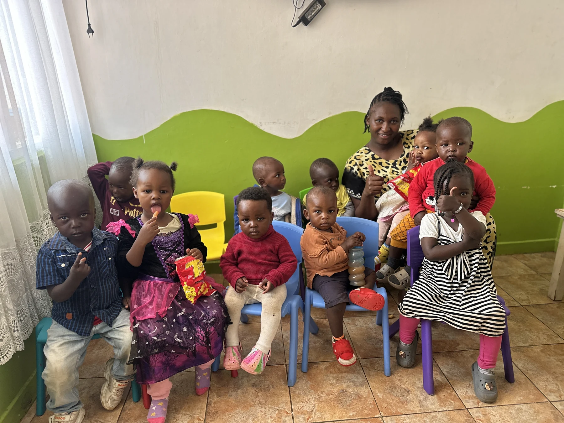 Children seated together with a caregiver in the Little Heaven playroom