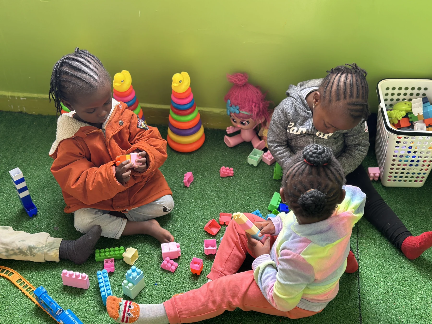 Children sharing blocks and colourful toys on the playroom floor